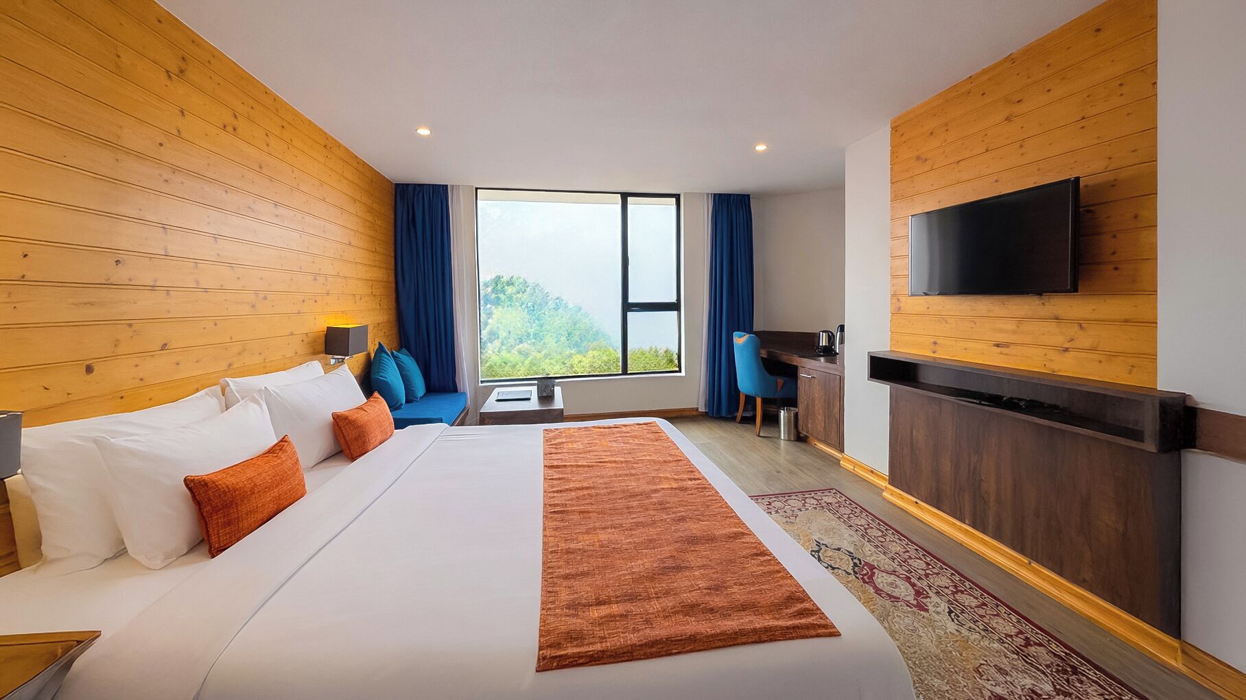 Habitación de hotel con una cama grande, un escritorio, un televisor y vistas a zonas verdes.