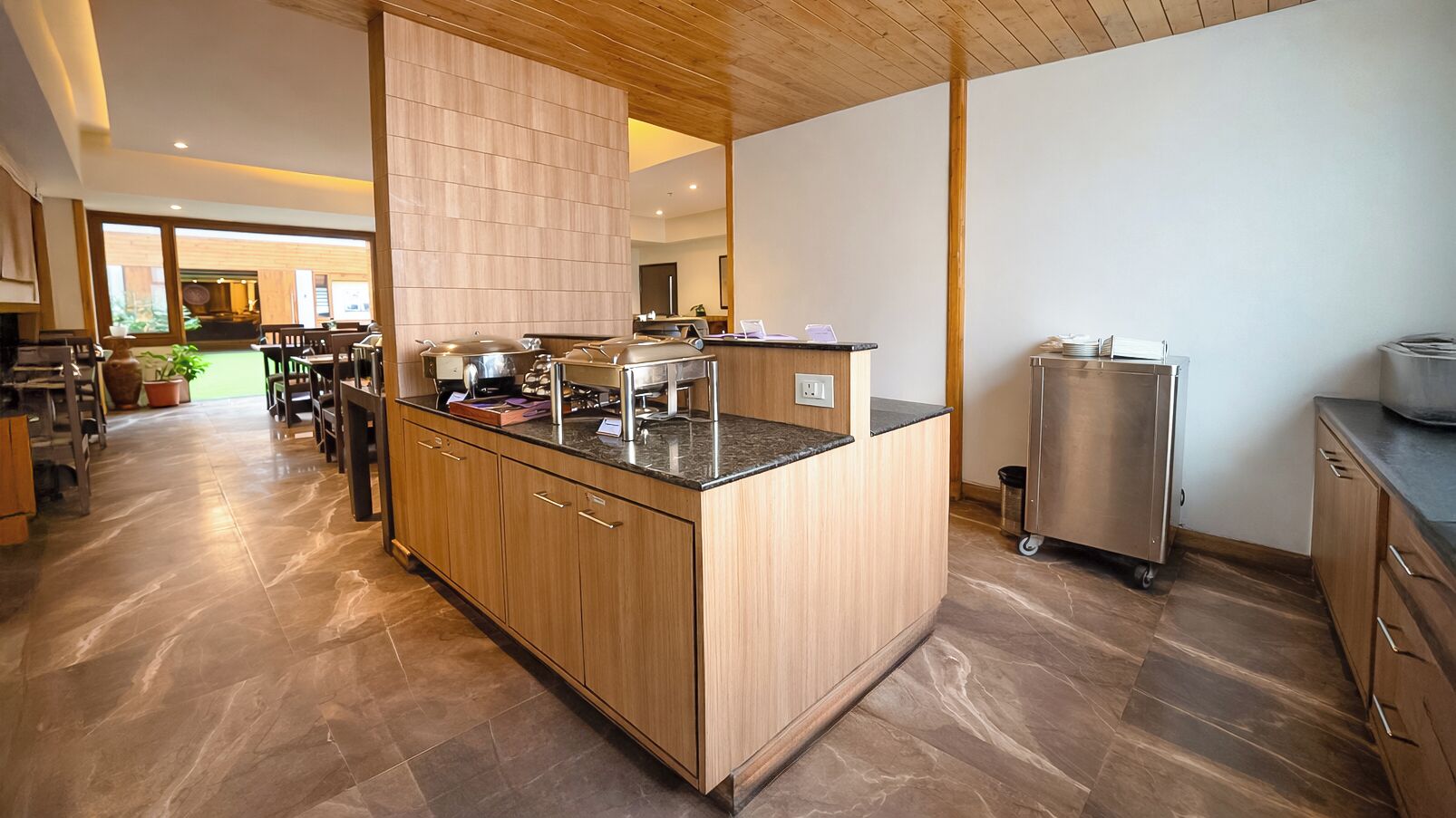 A modern kitchen with a central island, wooden cabinets, and a stainless steel refrigerator.