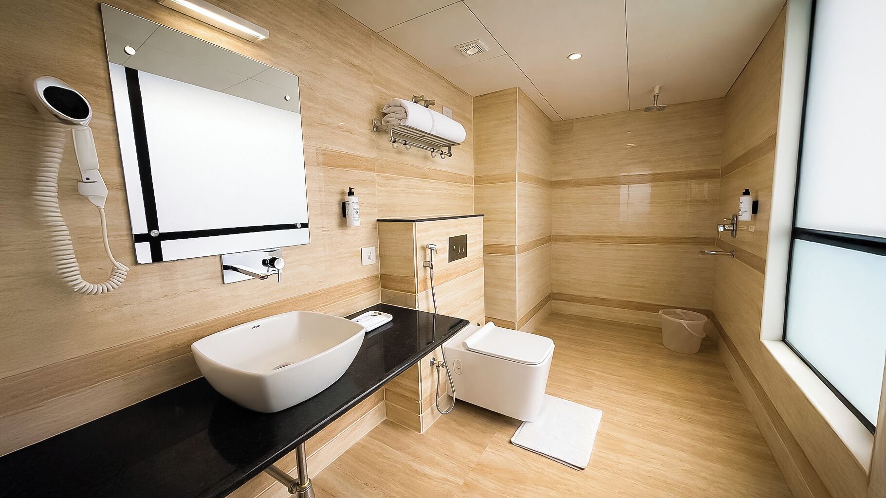 A modern bathroom with a large sink, a mirror, a hairdryer, a towel rack, and a shower.
