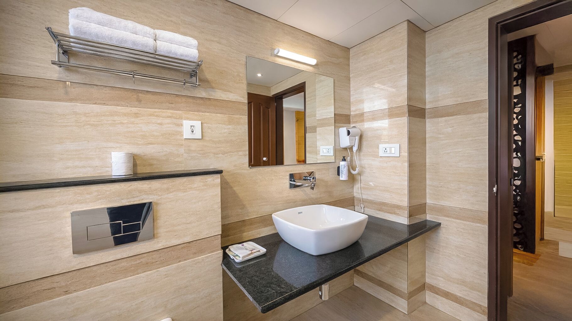 A modern bathroom with a large mirror, a white sink, a towel rack, and a hairdryer.