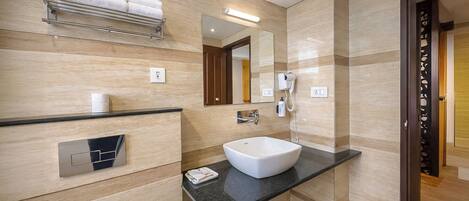 A modern bathroom with a large mirror, a white sink, a towel rack, and a hairdryer.