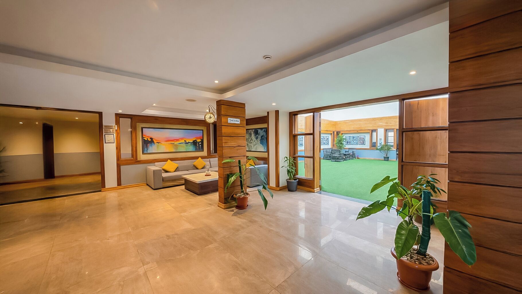 A spacious lobby with a large painting, a sofa, and potted plants.