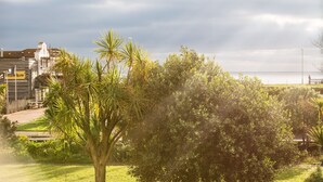 A coastal landscape with palm trees and a building with a sign reading "EASTERN ISLAND". - Beach in Reach - group house for up to 14 with sea views (Eastbourne)