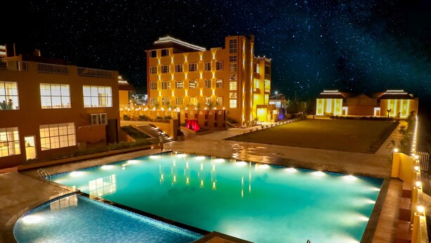 Una piscina con vista al cielo nocturno, edificios iluminados y una terraza bien iluminada.