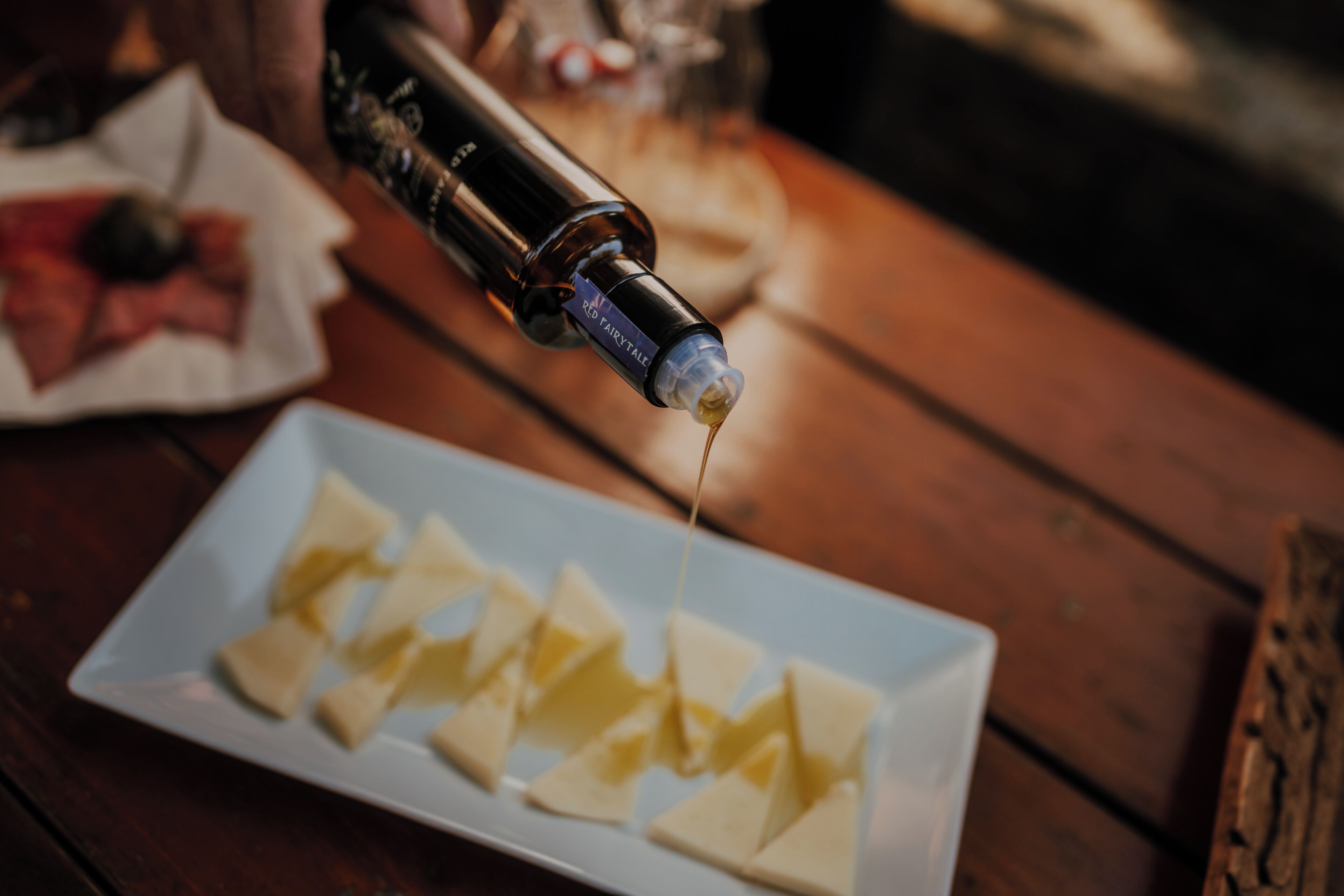 Una botella vertiendo un líquido amarillo sobre un plato con porciones de comida triangular.