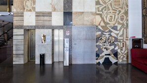 Un espace d’ascenseur moderne avec un mur décoré de motifs, un canapé rouge et une poubelle.