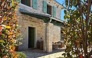 Un bâtiment en pierre doté d’un patio couvert, de mobilier d’extérieur et d’une porte.