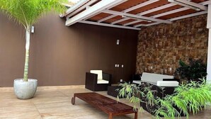 A modern outdoor seating area with a stone wall, a wooden bench, and potted plants. - Apto 2/ Q próximo ao Hospital premium (Goiania)