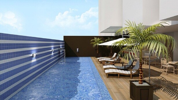 A rooftop pool with blue tiles and lounge chairs, surrounded by palm trees and a modern building. - Apto 2/ Q próximo ao Hospital premium (Goiania)