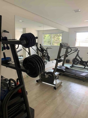 Uma academia com equipamentos de musculação, esteiras e bicicletas ergométricas.