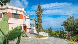 A Mediterranean-style villa with a stone courtyard, a cactus plant, and a view of the sea. - DN Beach Coast Villa (Zakynthos)