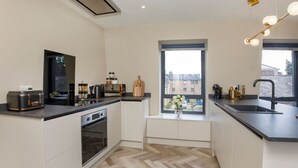 A modern kitchen with a built-in oven, a large window, and a view of the city. - The Tree house, York (York)