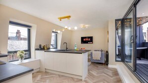 A modern kitchen with a central island, a built-in sink, and a large window. - The Tree house, York (York)