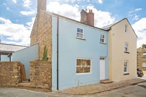 A two-story house with a light blue facade, a stone chimney, and a white door. - The Old Vet’s House, Masham (Masham)