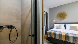 Moderni hotellihuone, jossa on suuri sänky, suihkutila ja koristeellinen seinäelementti.