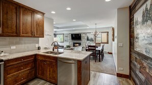 A modern kitchen with wooden cabinets, a built-in dishwasher, and a stone backsplash.