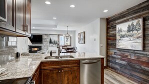 A modern kitchen with wooden cabinets, a granite countertop, and a built-in dishwasher.