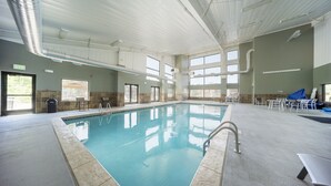 An indoor swimming pool with clear water, tiled walls, and a ceiling with visible ductwork.