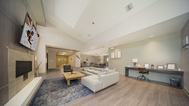 A spacious living area with a sofa, coffee table, and a flat-screen TV mounted on the wall.