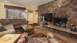 A living room with a stone fireplace, a television, a sofa, and a coffee table.
