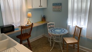 A small kitchen with a microwave, a wooden chair, a round table, and a cabinet above the counter. - Beach Side Studio #1 Apts by RedAwning (Norfolk)