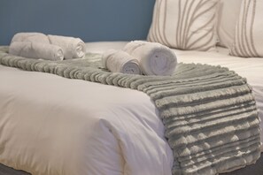 A neatly made bed with white linens and a grey textured blanket. - The Tokyo 1508 (Cape Town)
