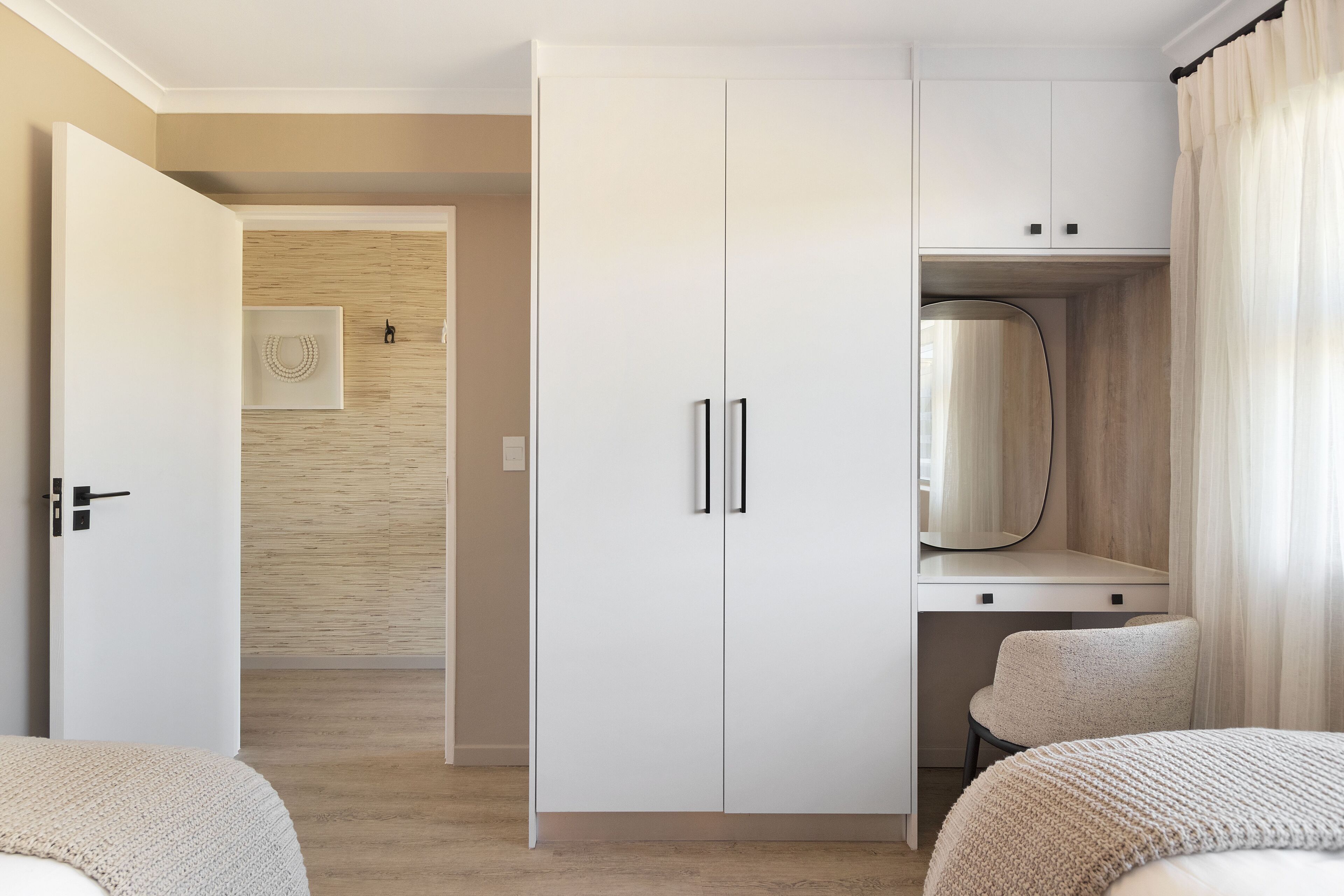 Um quarto com cama, guarda-roupa, escrivaninha e cadeira.
