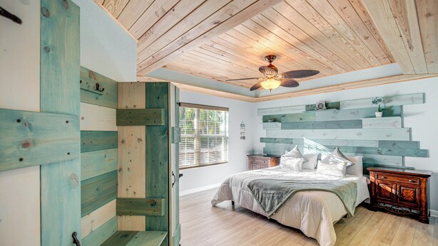A bedroom with a wooden ceiling, a bed with pillows, a nightstand, and a window with blinds. - Fort Myers Getaway w/ Hendry Creek Access! (Fort Myers)