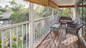 A covered porch with wicker furniture, a small table, and a view of greenery and buildings. - Fort Myers Getaway w/ Hendry Creek Access! (Fort Myers)
