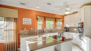 A modern kitchen with white cabinets, a granite countertop, and a large island. - Fort Myers Getaway w/ Hendry Creek Access! (Fort Myers)