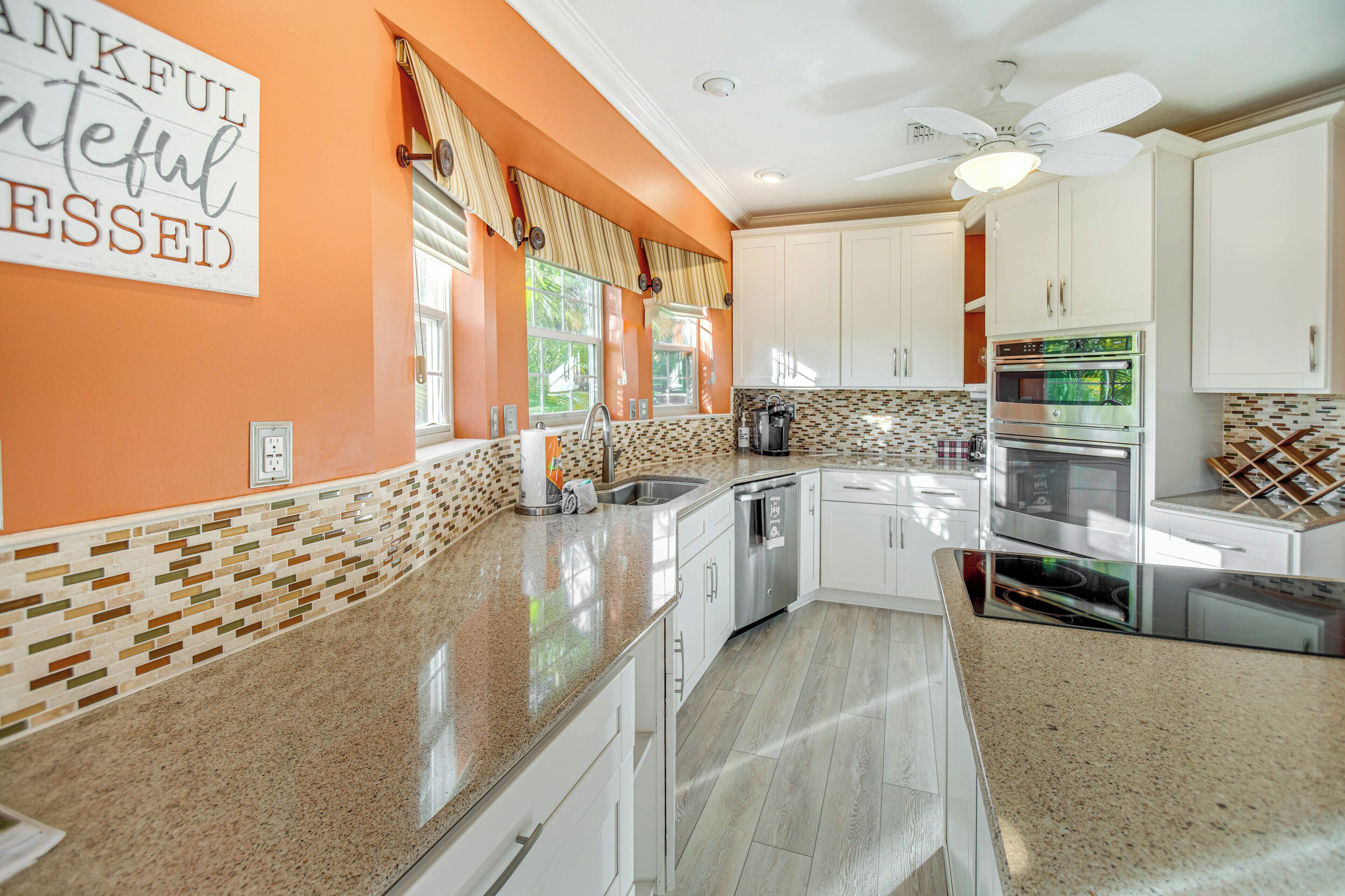 A kitchen with white cabinets, a granite countertop, and a ceiling fan.