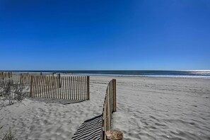 A sandy beach with a wooden fence and a clear blue sky. - Beachfront Condo w/ Balcony & Pool in Myrtle Beach (Myrtle Beach)