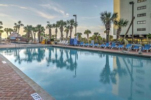 A swimming pool with lounge chairs and palm trees. - Beachfront Condo w/ Balcony & Pool in Myrtle Beach (Myrtle Beach)