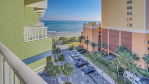 Ein Hotel mit Blick auf den Strand, einem Parkplatz und einem grünen Gebäude mit Balkon.
