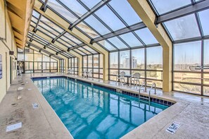 An indoor swimming pool with clear glass ceilings, a tiled floor, and a view of the surrounding landscape. - Beachfront Condo w/ Balcony & Pool in Myrtle Beach (Myrtle Beach)
