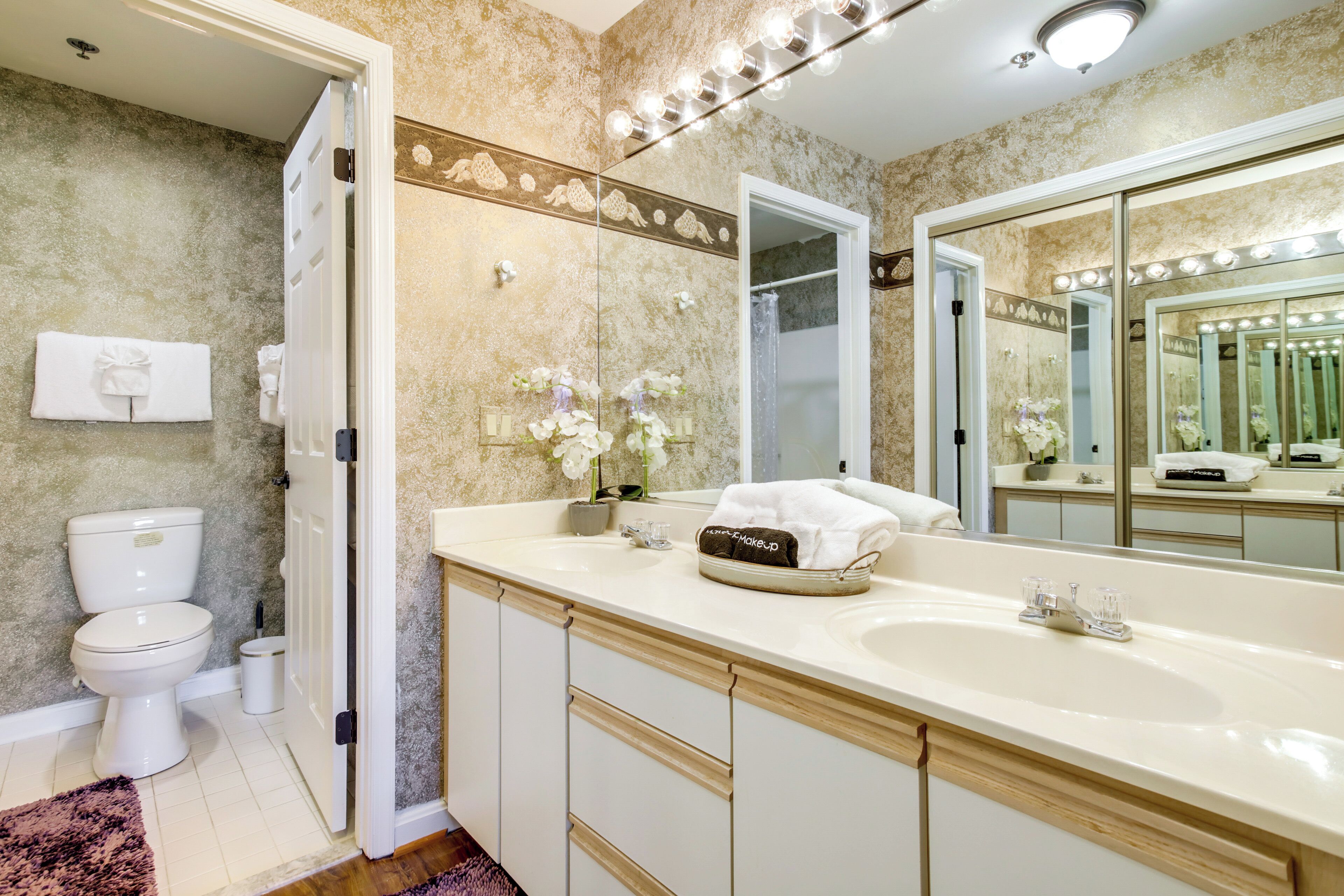 A bathroom with a large mirror, a sink, and a toilet.