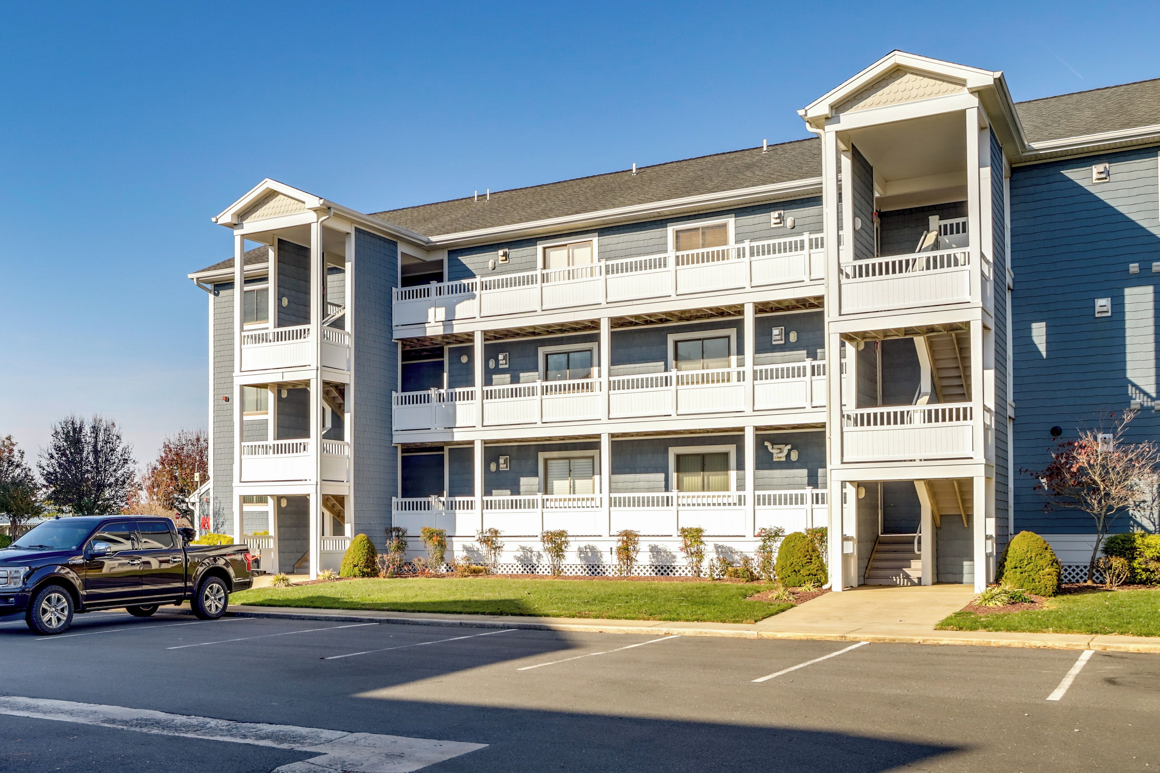 A multi-story building with a central courtyard, balconies, and a parking lot.