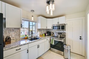 A modern kitchen with white cabinets, a granite countertop, stainless steel appliances, and a window with a view of the outdoors. - 1 Mi to Downtown Salem: Studio w/ Fire Pit Access (Salem)