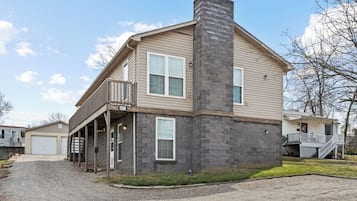 A two-story house with a stone chimney, a covered porch, and a garage.