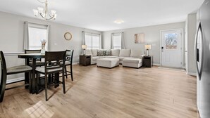 A spacious living room with a dining area, a sofa set, and a chandelier.