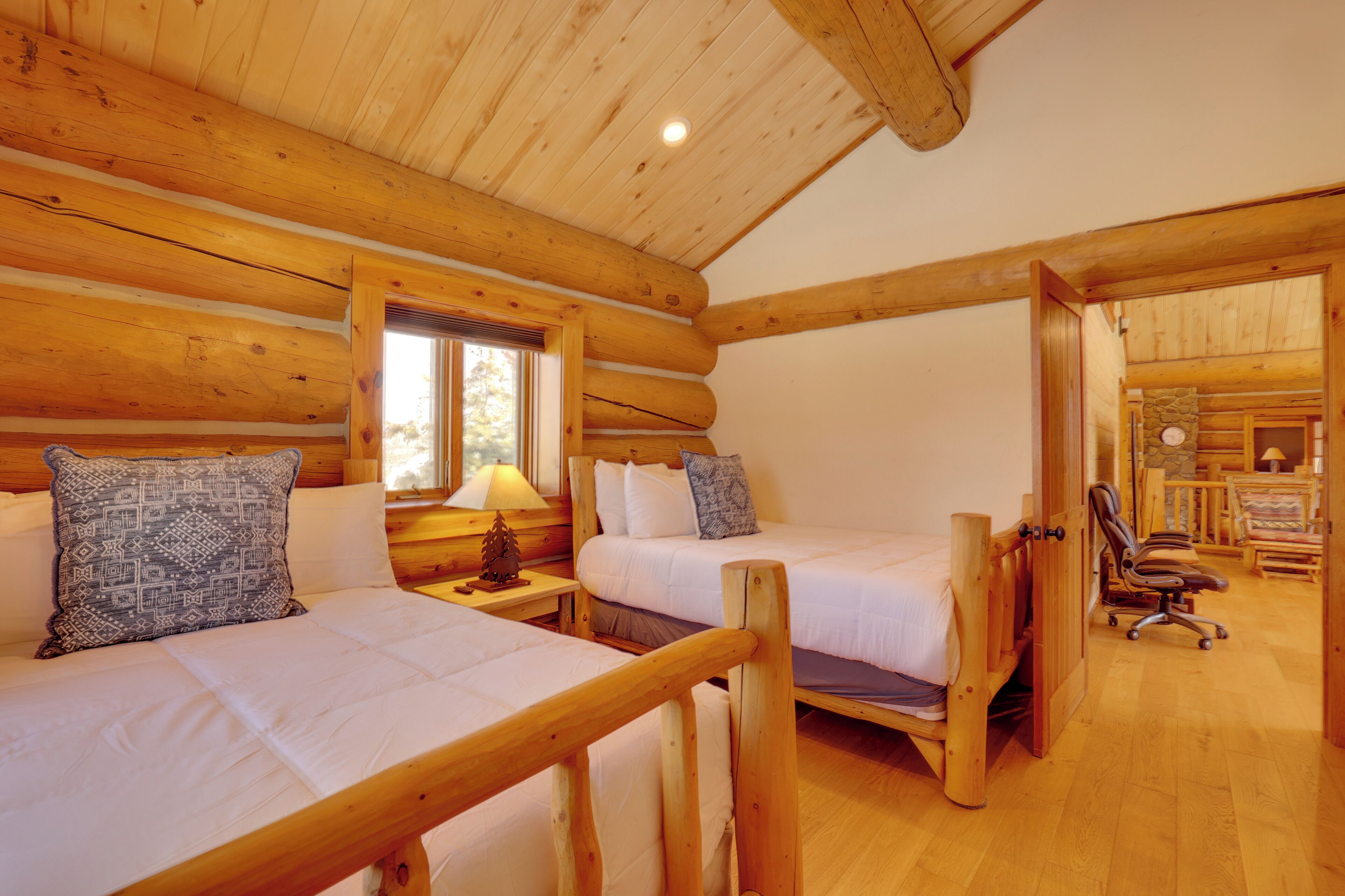 A log cabin bedroom with two beds, wooden walls, and a cozy atmosphere.