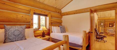 A log cabin bedroom with two beds, wooden walls, and a cozy atmosphere.