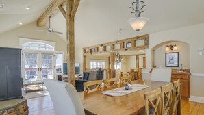 A spacious dining area with a wooden table and chairs, a stone fireplace, and a view of the outdoors.