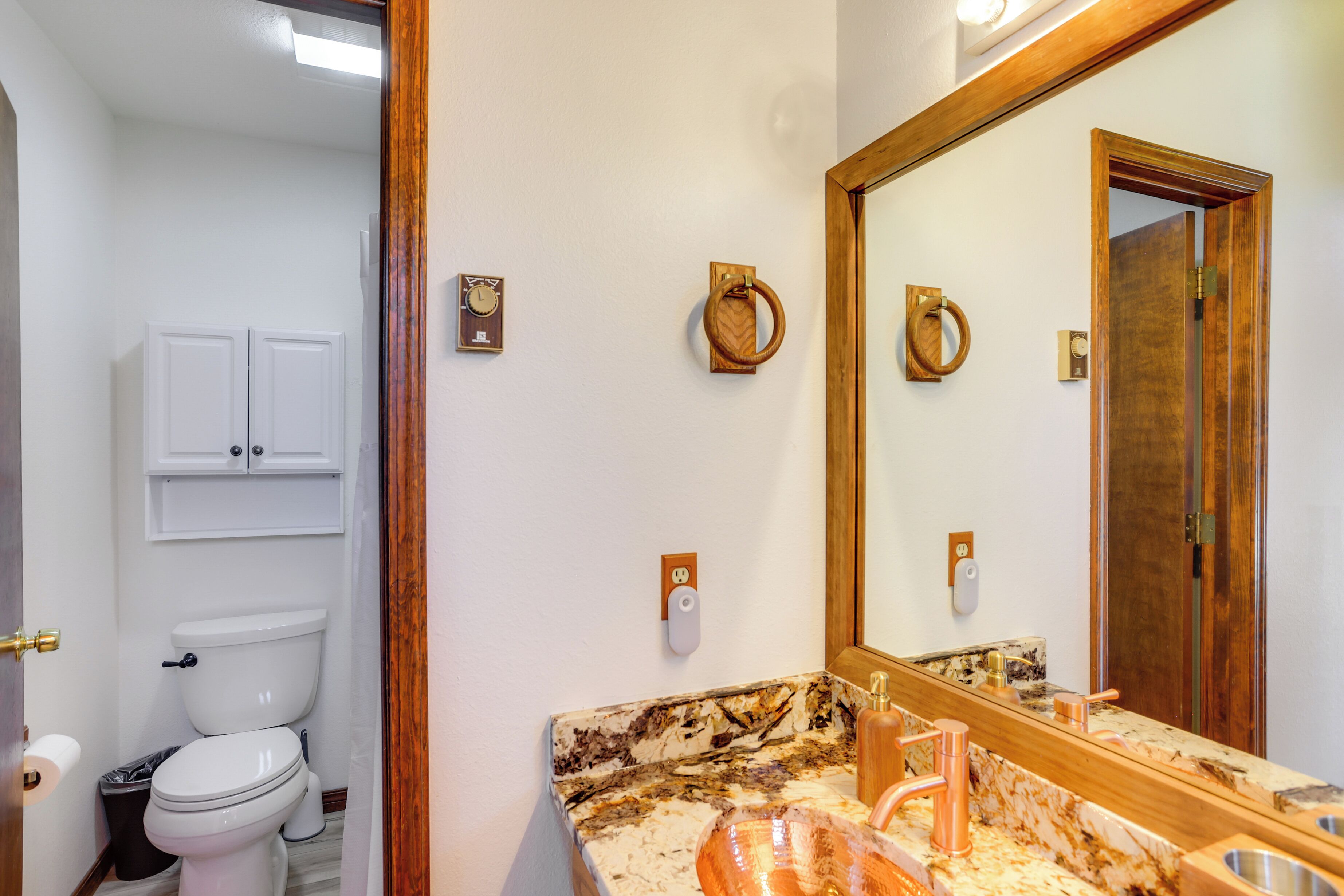 A bathroom with a marble sink, a large mirror, and a toilet.