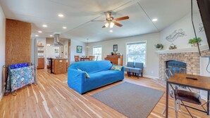 A spacious living room with a blue sofa, a dining table with chairs, a fireplace, and a kitchen area in the background. - Pet-friendly Canyon Lake Home ~ 3 Mi to Water! (Canyon Lake)