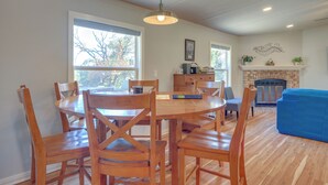 A dining area with a round wooden table and chairs, a fireplace, and a blue sofa in a living room. - Pet-friendly Canyon Lake Home ~ 3 Mi to Water! (Canyon Lake)