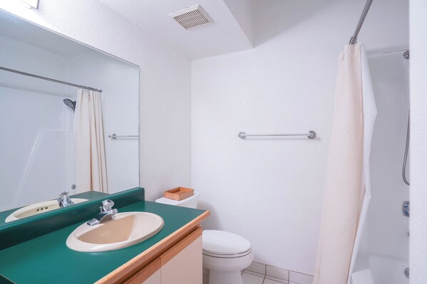 Un baño con lavamanos, espejo, inodoro y ducha.