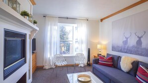 A living room with a fireplace, a sofa, two chairs, a coffee table, and a window with curtains. - Cozy Brian Head Condo: Walk to Navajo Express Lift (Brian Head)