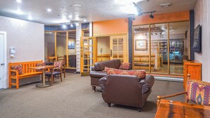 A cozy living area with a sofa, chairs, and a coffee table. There is a sliding glass door leading to a kitchen area. - Cozy Brian Head Condo: Walk to Navajo Express Lift (Brian Head)