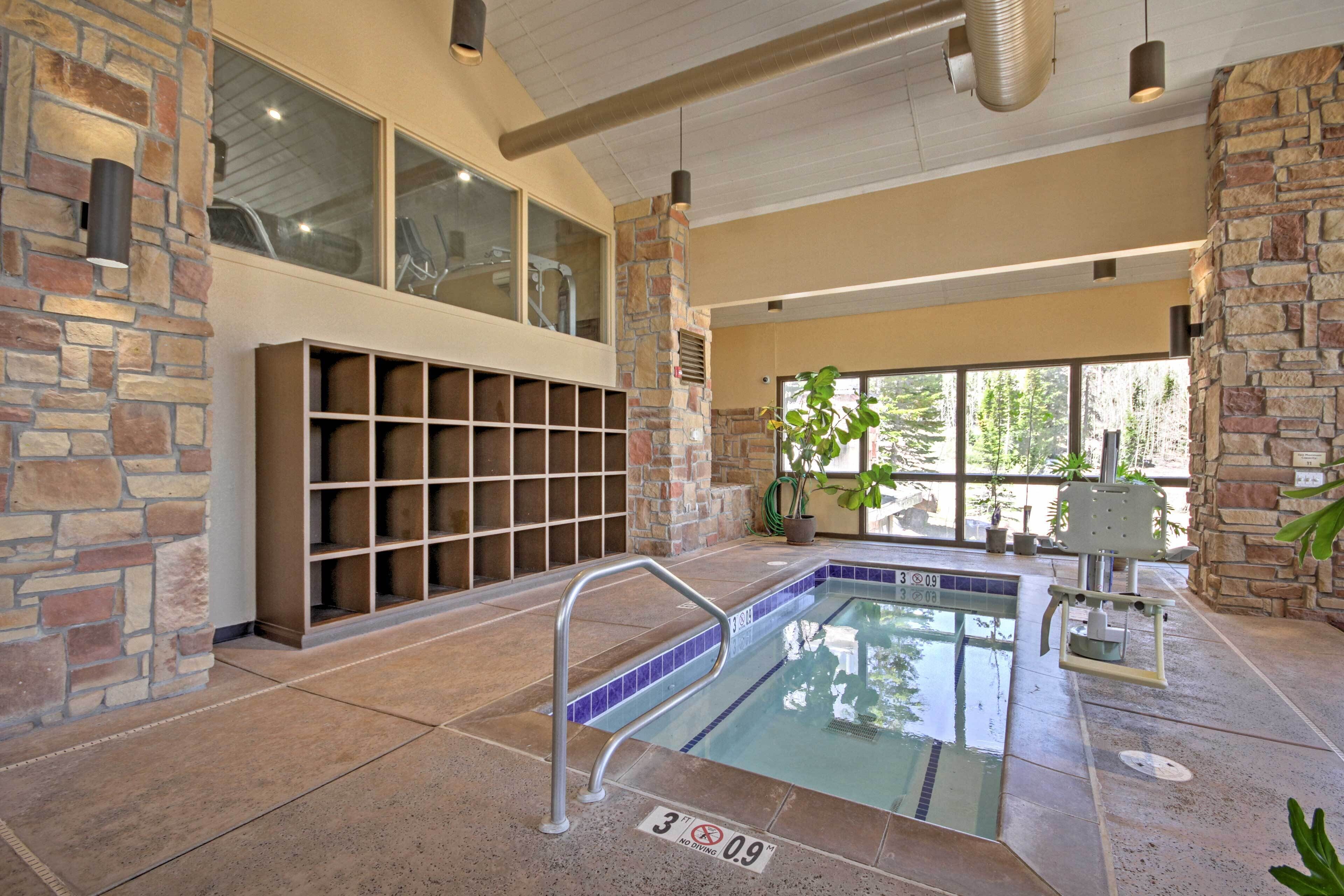 Una piscina interior con paredes de piedra, una zona de descanso integrada y vistas despejadas al exterior.